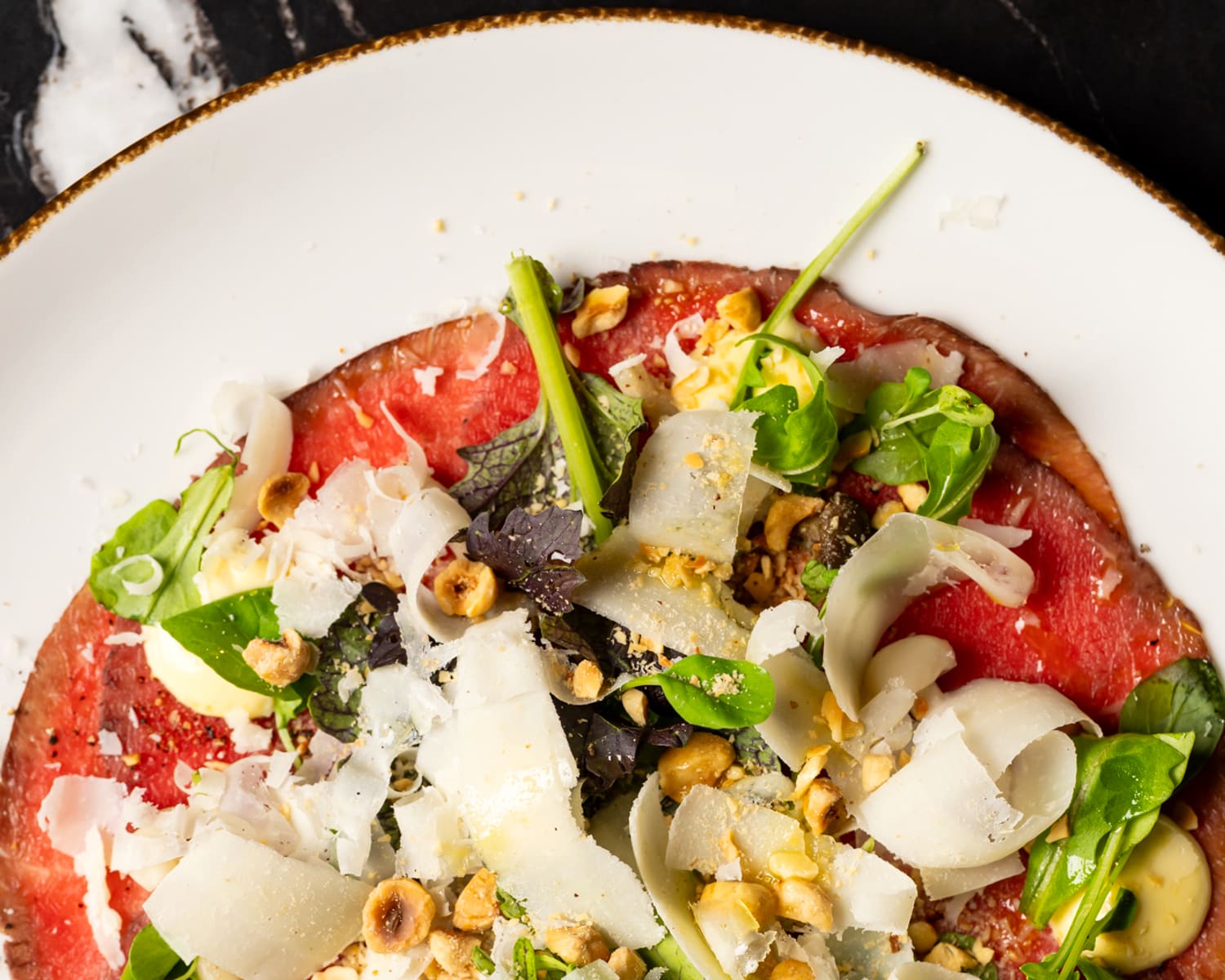 Beef carpaccio with pickled beech mushrooms, hazelnut emulsion, parmigiano, and greens at Notte Ristorante